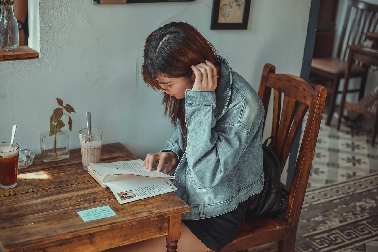 A young woman sitting in a café, reading a book while enjoying a coffee.Overseas education in UAE | Geoedutech.