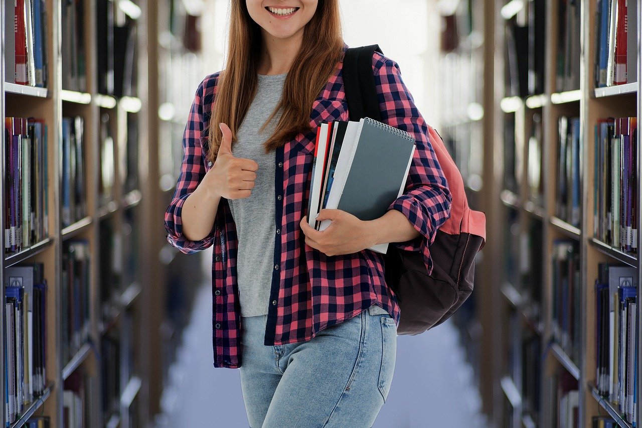 A collection of student books on shelves in a library, A gril with a books focus on organized educational resources.
